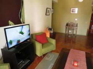 sala de estar con TV y silla verde en Buenos Aires Arthouse en Buenos Aires