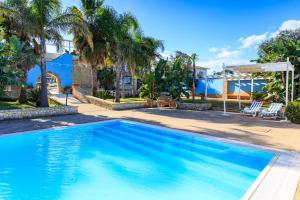una piscina in un cortile con palme di Borgo Marino Plemmirio a Siracusa
