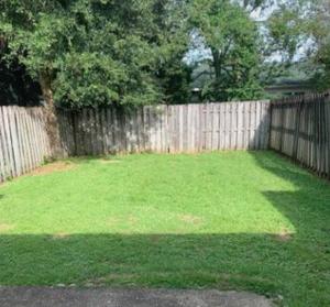 a backyard with a wooden fence and a grass yard at Charming 2 bdr 1 bath home fenced byard N Pensacola Pet Friendly Close to bases in Pensacola