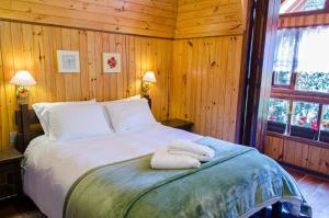 a bedroom with a bed with two towels on it at Chalés Recanto da Fonte Monte Verde - MG in Monte Verde