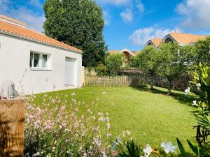 ein Hof mit einem weißen Haus und Blumen in der Unterkunft Le Clos de Jade - Appt 3 étoiles avec piscine partagée in Pornic