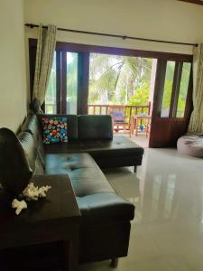 a living room with a leather couch and a table at Links Sunset Beach House in Amphoe Koh Samui