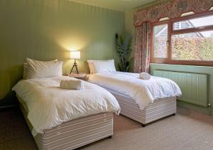 two beds in a bedroom with a window at Charming 3BD Cotswolds Family Retreat in Bourton on the Water