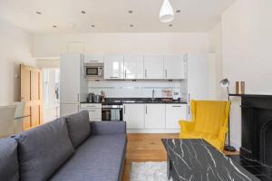 a living room with a gray couch and a kitchen at Stylish 1-Bed Flat in Prime Kensington Location in London