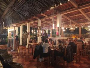 a group of people sitting at tables in a restaurant at Tiki Lodge Hotel de Charme in Santa Catalina