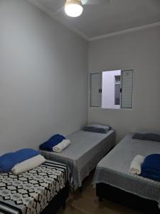 ein Zimmer mit zwei Betten und einem Spiegel in der Unterkunft Casa familiar lado do Santuário Nacional de Aparecida SP in Aparecida