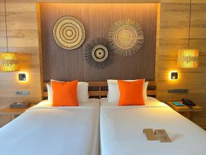 two beds in a hotel room with orange pillows at Ao Prao Resort in Ko Samed