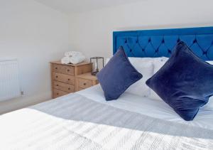 a bed with two blue pillows on top of it at Discovery Barn - Luxury 2 Bed Barn Conversion! in Cropthorne
