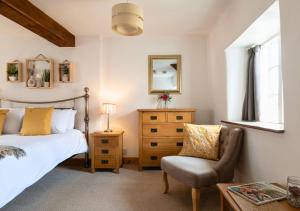 a bedroom with a bed and a chair and a mirror at Diston's Lane - Beautiful 2BD Home, Perfect For Family Retreat! in Chipping Norton