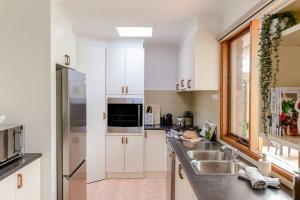 a kitchen with white cabinets and a sink at Eden Coast in Balcombe