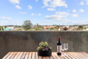 eine Flasche Wein und Gläser auf einem Tisch mit Pflanze in der Unterkunft Artist Abode: Stay in a Home That’s Also a Gallery in Melbourne