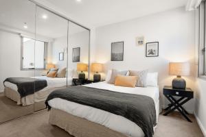 ein Schlafzimmer mit zwei Betten und einem Spiegel in der Unterkunft Artist Abode: Stay in a Home That’s Also a Gallery in Melbourne