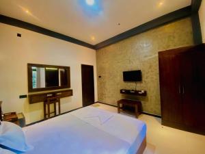 a bedroom with a large white bed and a television at Coffee House Resort Dambulla,Sigiriya in Dambulla