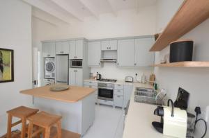 een keuken met witte kasten en een houten aanrechtblad bij Willow Cottage in Kaapstad +7 foto's