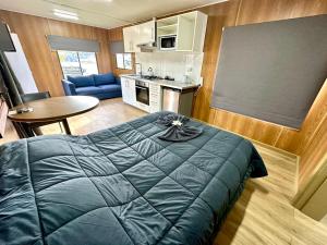 a bedroom with a blue bed and a kitchen at Corryong Caravan Park in Corryong