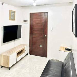a living room with a television and a wooden door at The Urban Haven Cebu 2Bedrooms 4beds Condo in Mandaue City
