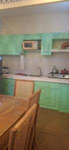 a kitchen with green cabinets and a table with chairs at Tiny house in city proper in Puerto Princesa City