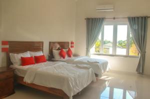 a bedroom with two beds with red pillows and a window at Sokha Home in Bahal