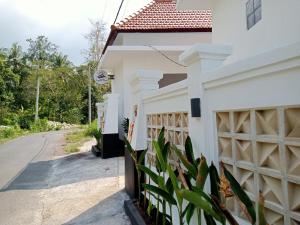 a white house with a gate and a road at Layana One in Klungkung