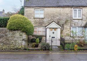 a stone house with a white door and a fence at Honeypot Cottage - Charming Bolthole in Stow! in Stow on the Wold