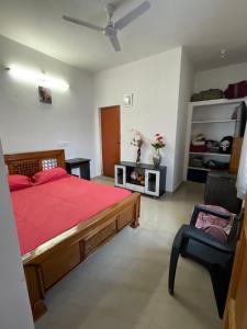 a bedroom with a red bed and a chair at Bliss-family Homestay in Karaikal