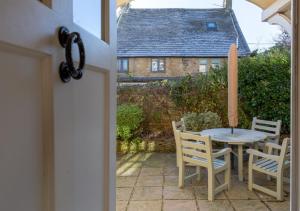 un patio con tavolo, sedie e una casa di Jasmine Cottage - 2 Bedroom in Heart of Bourton! a Bourton on the Water
