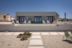a house with a swimming pool and lawn chairs at LELE' Guesthouse in Scoglitti