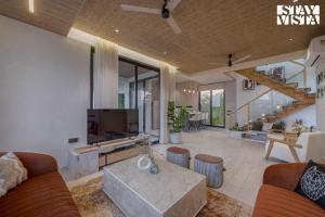 a living room with a couch and a tv at StayVista at Villa De Suku with Pool, Balcony in Igatpuri