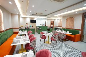 a restaurant with white tables and red chairs at IRA By Orchid Noida in Noida