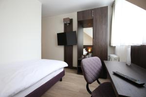 a hotel room with a bed and a desk with a computer at Fährhaus Hotel am Rhein by Mayburgh in Düsseldorf +18 photos