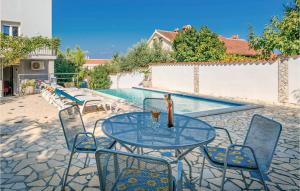 a table with chairs and a drink on it next to a pool at 1 Bedroom Amazing Apartment In Banjole in Banjole +20 photos