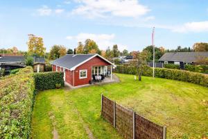 a red house in a yard with a fence at Cozy House In Grenaa, Close To A Lovely Sandy Beach in Grenå