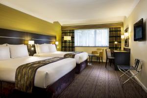 a hotel room with two beds and a desk at Holiday Inn London Gatwick - Worth by IHG in Crawley