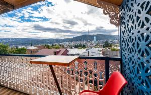 第比利斯Apart View Hotel & Spa的阳台配有木桌和红色椅子