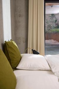 a bed with green and white pillows next to a window at Marselisborg Allé 9 B in Aarhus