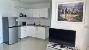 a kitchen with a refrigerator and a tv in it at Grandblue condominium 405,406 in Ban Tha Fat