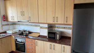a kitchen with wooden cabinets and a stainless steel refrigerator at Casa Frijol 20metres from the beach in Los Alcázares