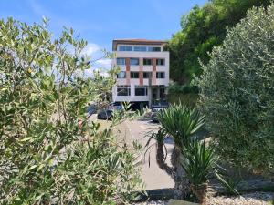 a building in the middle of a garden with trees at Hotel Oleander - Oleander Resort in Strunjan