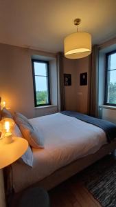 a bedroom with a large bed with two windows at Les Grands Gîtes de Cancale, gîtes de charme avec jacuzzi in La Coudre