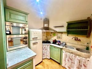 a kitchen with green cabinets and a white refrigerator at Da Tommaso in centro in Prato