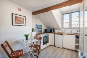 eine Küche mit weißen Schränken und einem Tisch und Stühlen in der Unterkunft Le Prestige Grenoble hypercentre in Grenoble + 10 Fotos