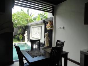 mesa de comedor con 4 sillas y piscina en Alit Bali Villa, en Canggu