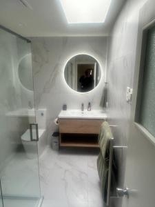 a white bathroom with a sink and a mirror at Manorburn Apartments Luxury Studio Apartment Central Otago in Ranfurly