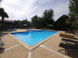 a large blue swimming pool with chairs and trees at Les Chalets de Grazimis in Condom