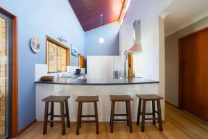 a kitchen with three bar stools and a counter at Peninsula in Sawtell