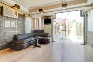 a waiting room with a leather couch and a table at Hotel O Mukut Mahal in Meerut