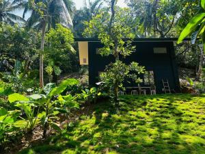 a black house in the middle of a garden at Casita Ysla Tiny Home with garden kitchen wifi 2 scooters in El Nido