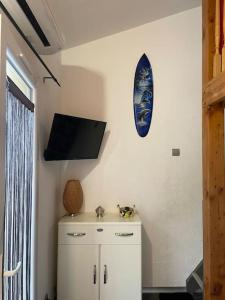 a room with a tv on the wall and a cabinet at Maison cosy Santa Barbara in Le Barcarès