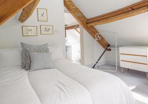 a large white bed in a room with wooden ceilings at Mill House Cottage - Star Stay on The Cotswold Way in Harescombe