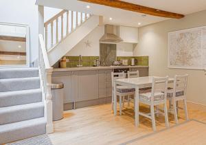 a kitchen with a table and chairs and a staircase at Mill House Cottage - Star Stay on The Cotswold Way in Harescombe